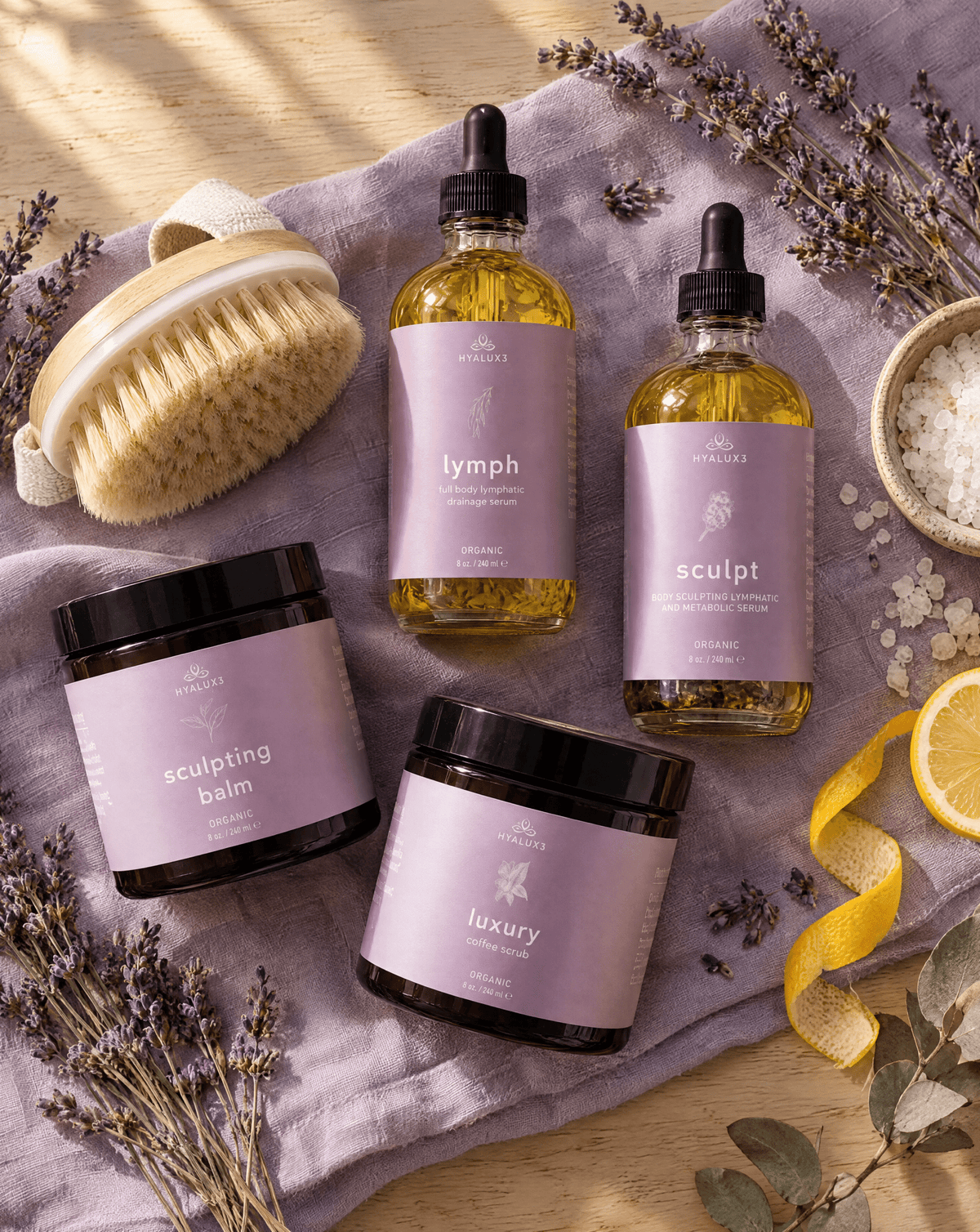 Hyaluxe Lymphatic Flow & Fat Release Body Bundle products laid out on lavender linen